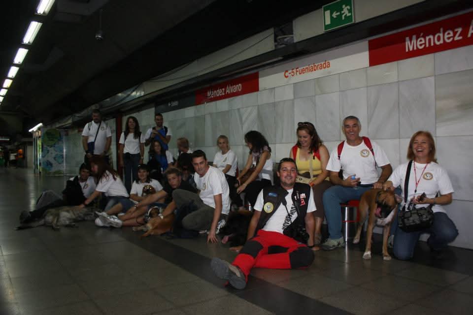 Grupo posa en una estación junto a un maniquí de prácticas de reanimación tendido en el suelo; los carteles indican Méndez Álvaro y C-5 Fuenlabrada.