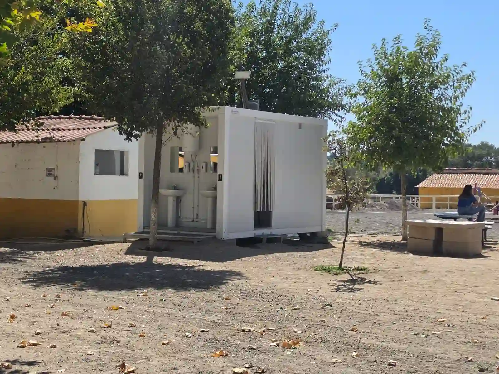 Edificio bajo y patio exterior con árboles y mobiliario.