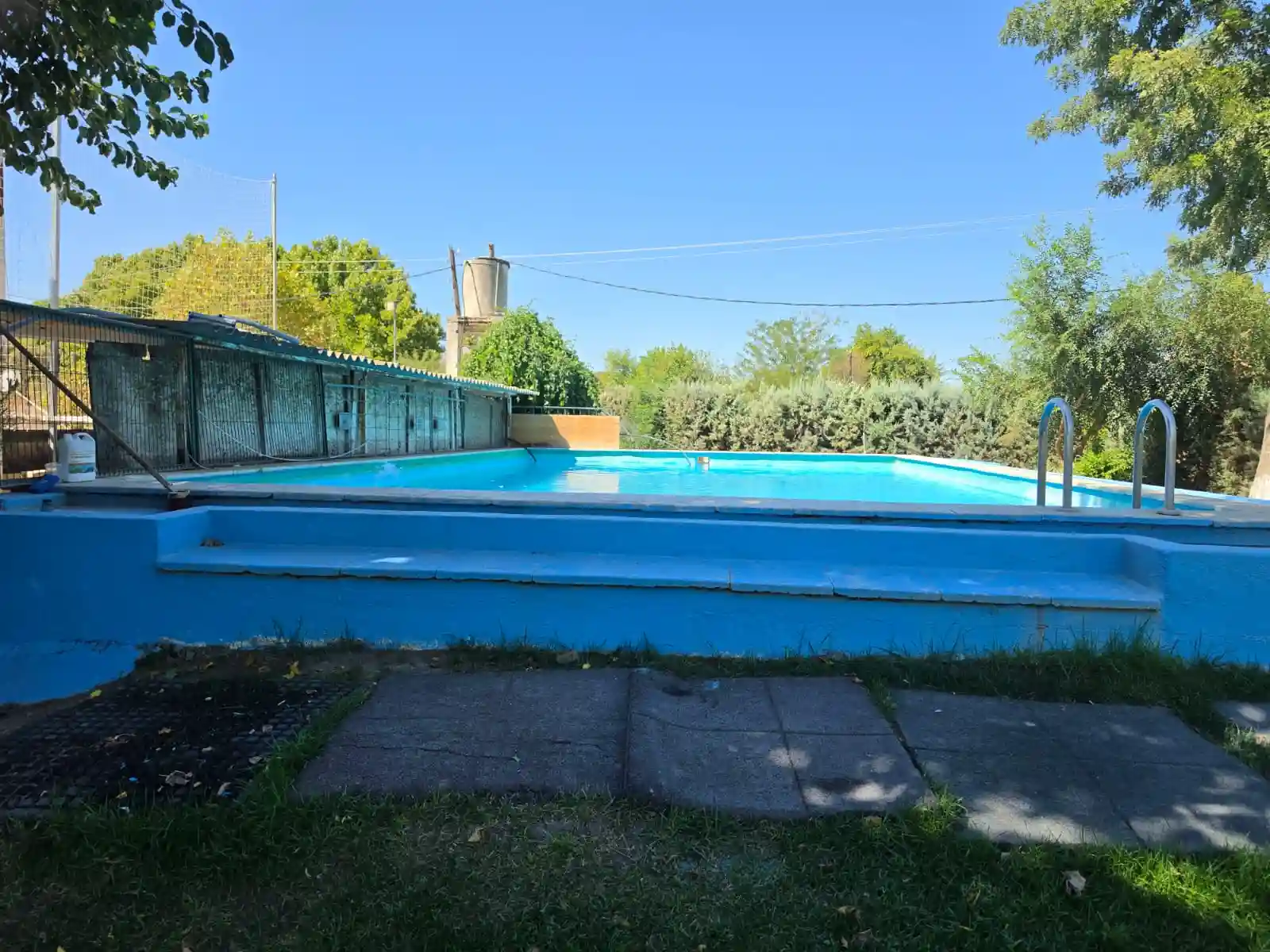 Piscina exterior junto a una estructura cubierta.